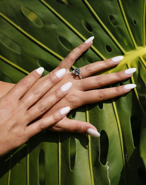 Mãos com unhas saudáveis sobre folha verde